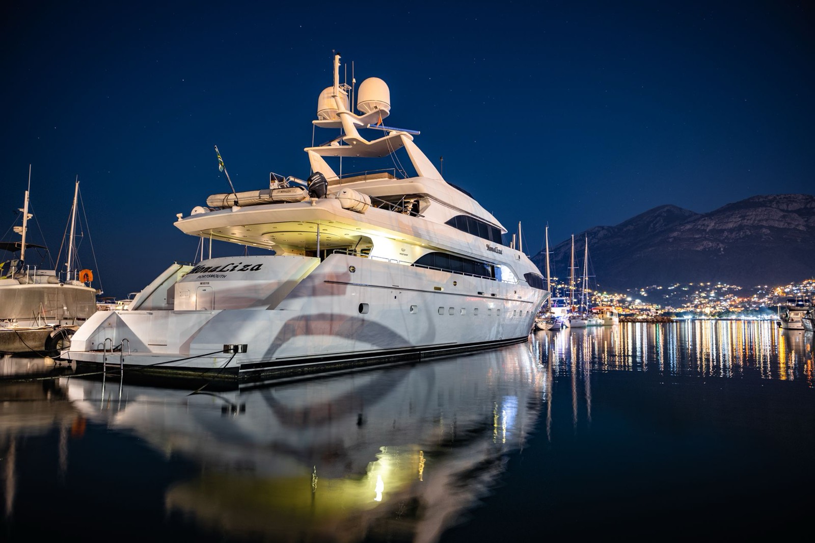Motor yacht lit at its berth at night in a calm marina